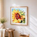 A golden sunflower in watercolour cross stitch artwork displayed on wall as home decor
