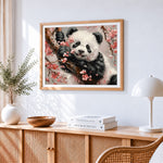 Adorable panda in cherry blossoms cross stitch artwork displayed on wall as home decor