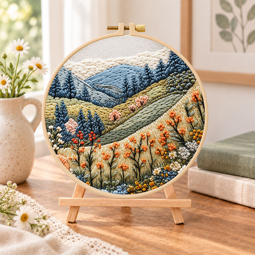 Alpine wildflower slopes embroidery kit finished hoop displayed on a wooden stand as cozy tabletop decor