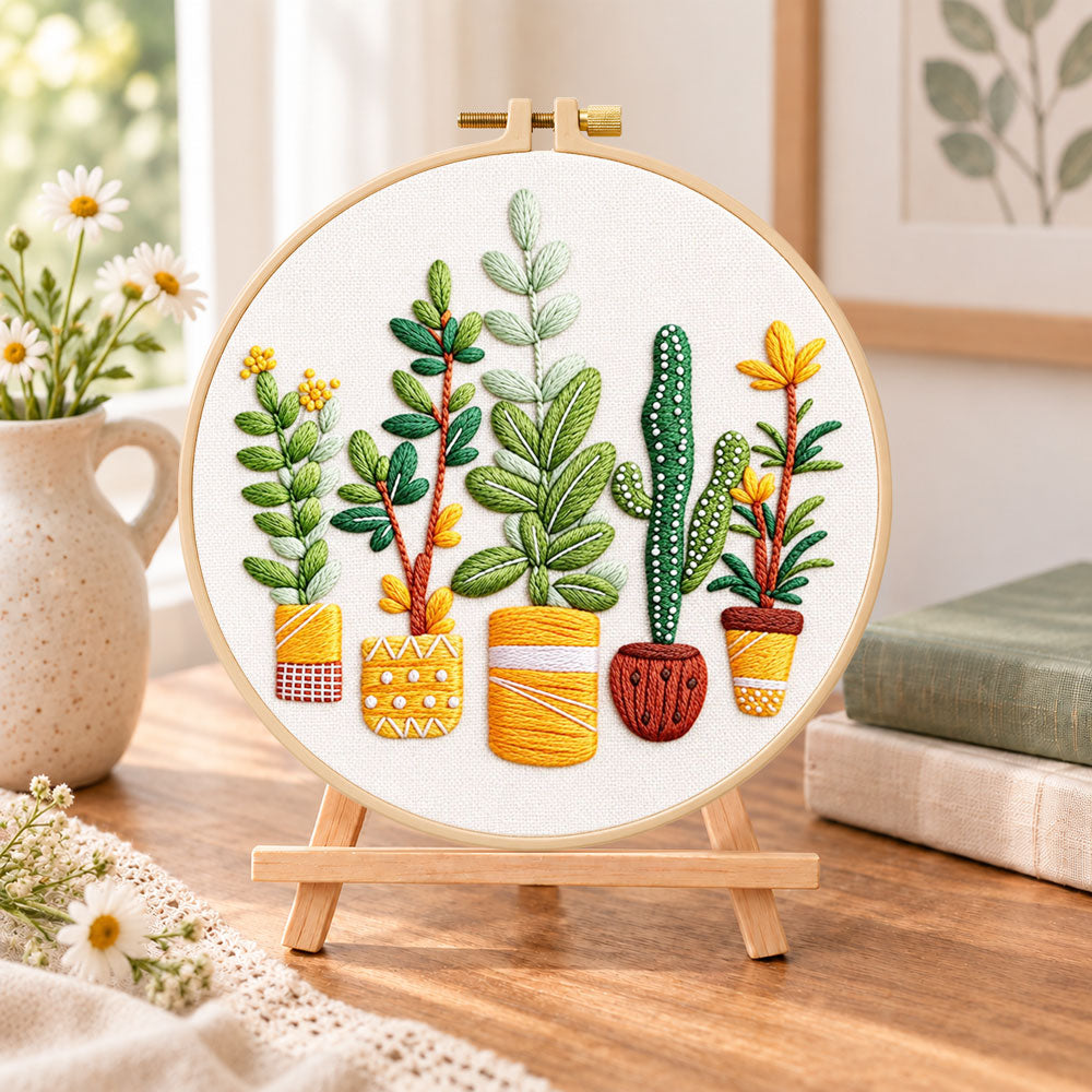 Assorted houseplants embroidery kit finished hoop displayed on a wooden stand as cosy tabletop decor