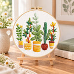 Assorted houseplants embroidery kit finished hoop displayed on a wooden stand as cosy tabletop decor