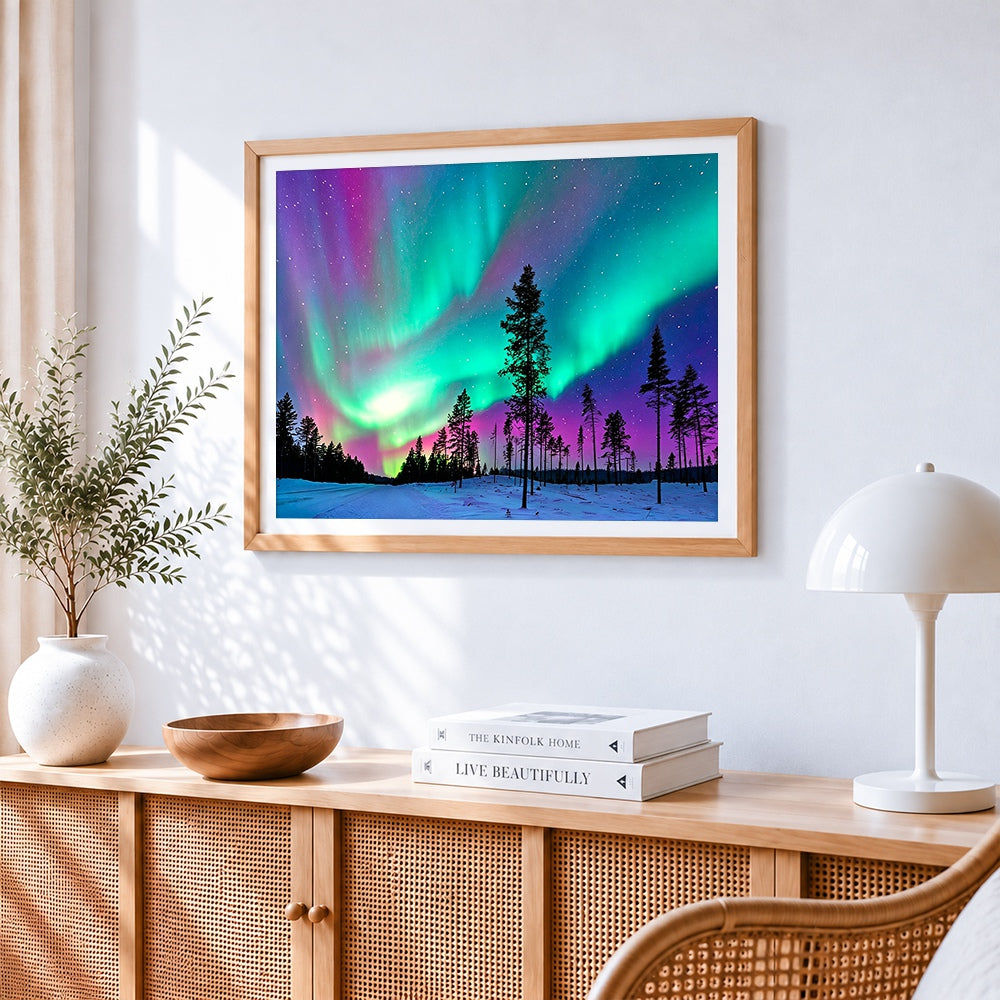 Aurora borealis over snowy forest cross stitch artwork displayed on wall as home decor