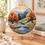 Autumn creek and trees embroidery kit finished hoop displayed on a wooden stand as cozy tabletop decor