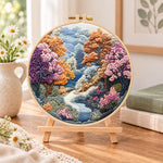 Autumn forest stream embroidery kit finished hoop displayed on a wooden stand as cozy tabletop decor