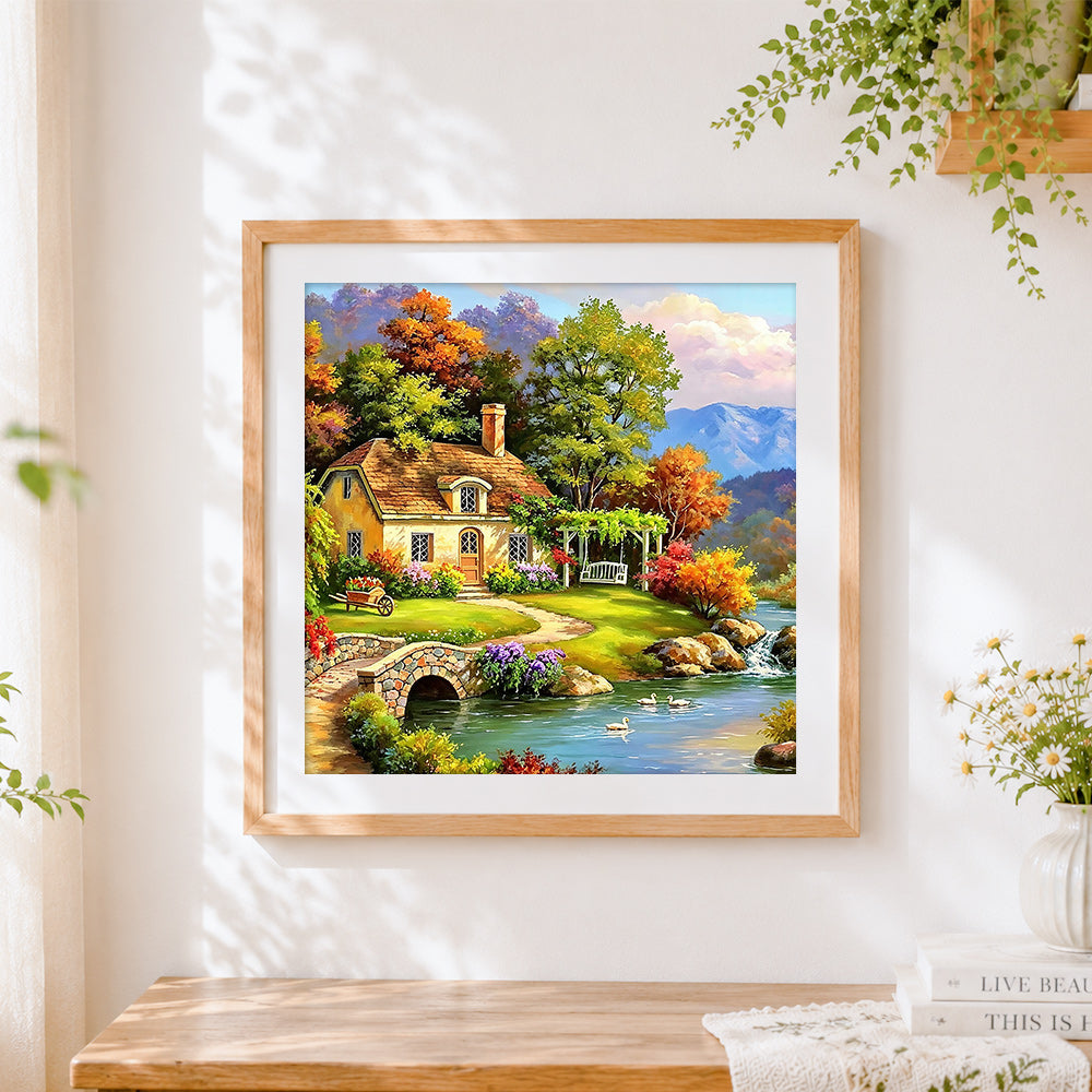 Finished autumn lake cottage with swans cross stitch artwork displayed