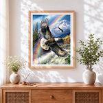 Finished bald eagle flying over mountains and rainbow cross stitch artwork displayed