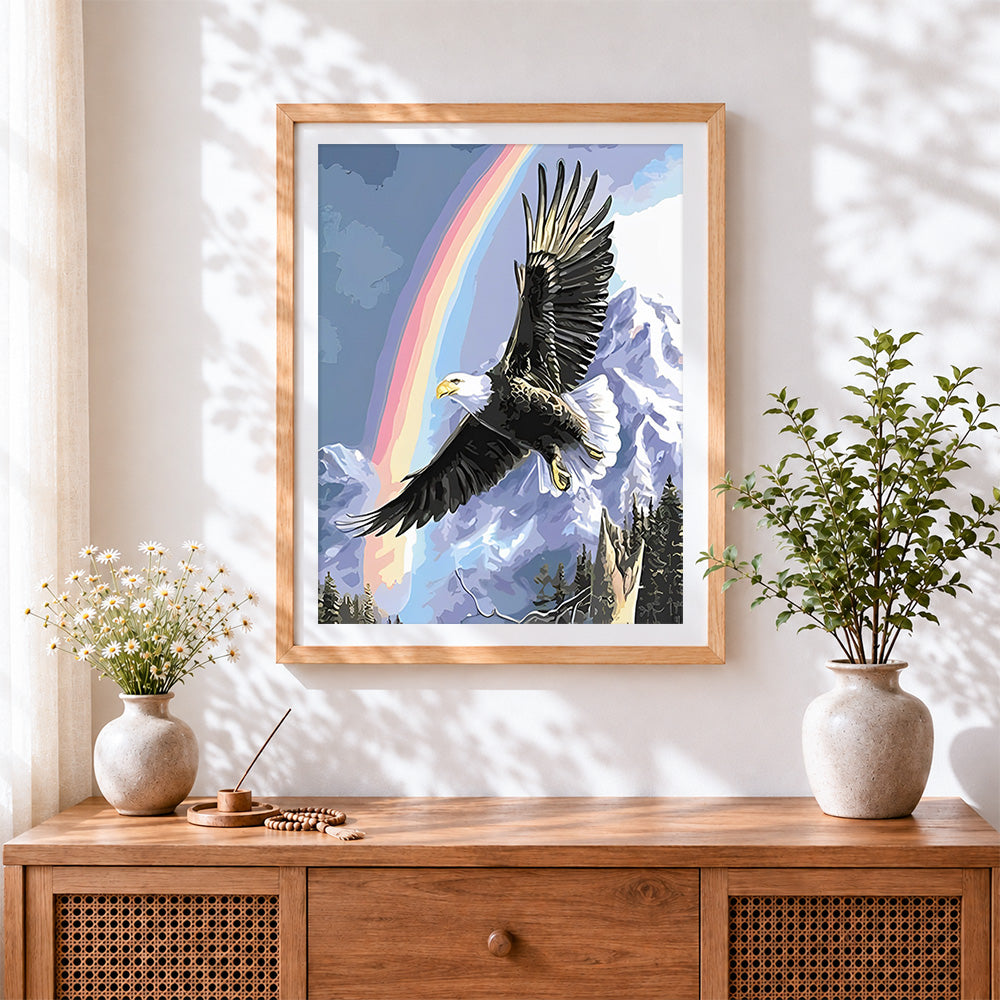 Finished bald eagle rainbow and snowy mountain cross stitch artwork displayed