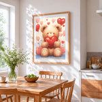 Bear holding a red heart cross stitch artwork displayed on wall as home decor