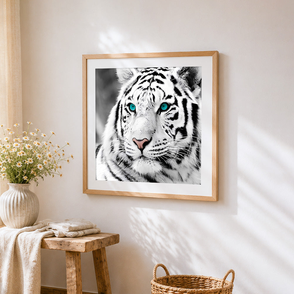 Black and white white tiger with blue eyes cross stitch artwork displayed on wall as home decor