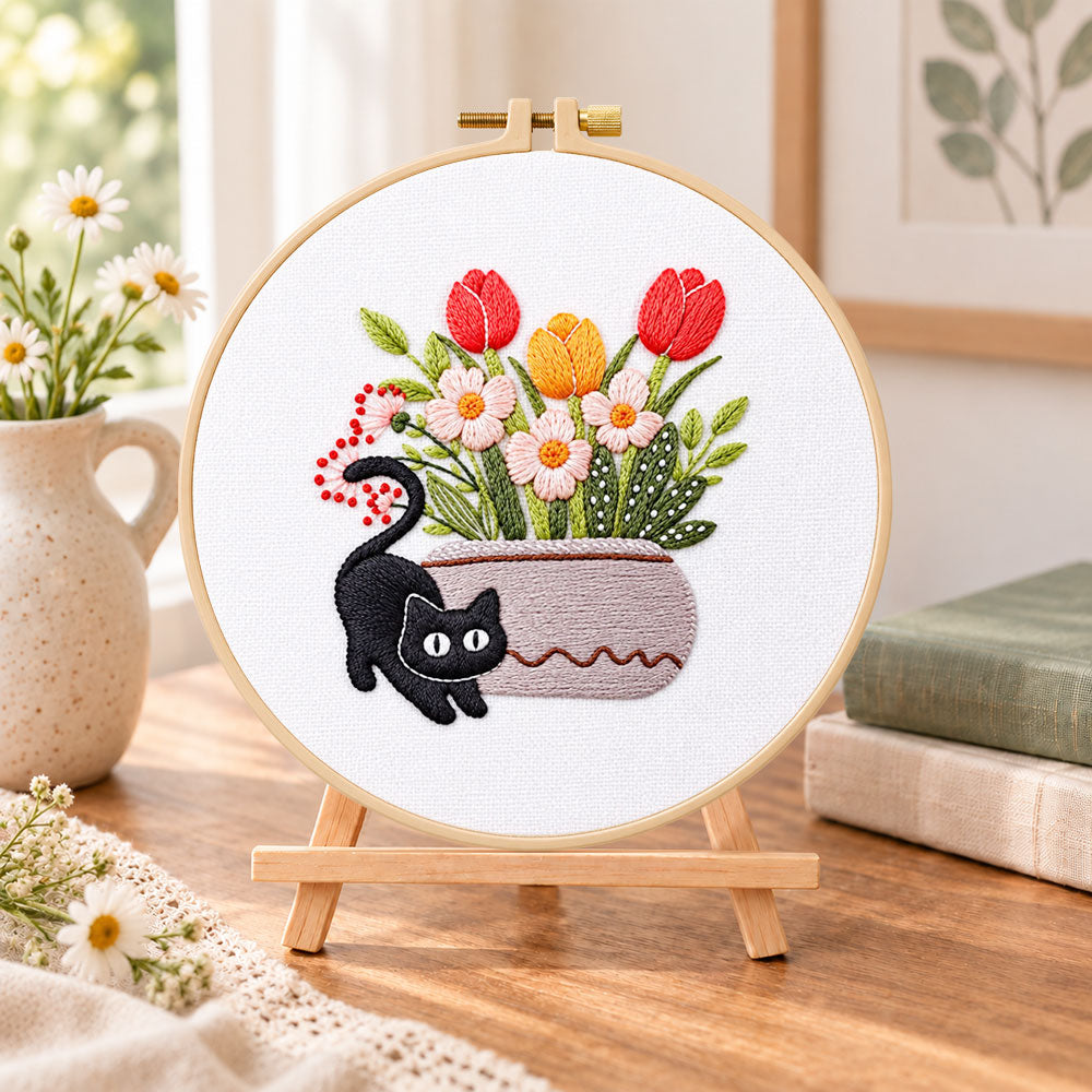 Black cat and tulips embroidery kit finished hoop displayed on a wooden stand as cosy tabletop decor