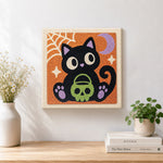 Finished black cat holding skull treat bucket artwork displayed on a wall