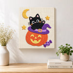 Finished black cat inside pumpkin hat artwork displayed on a wall