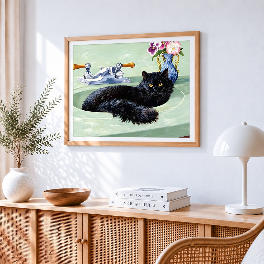 Black cat sitting in a green sink cross stitch artwork displayed on wall as home decor