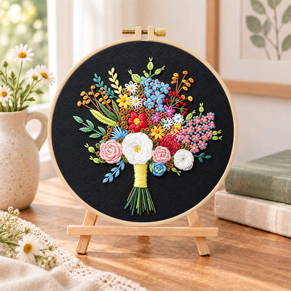 Black fabric flower bouquet embroidery kit finished hoop displayed on a wooden stand as cosy tabletop decor
