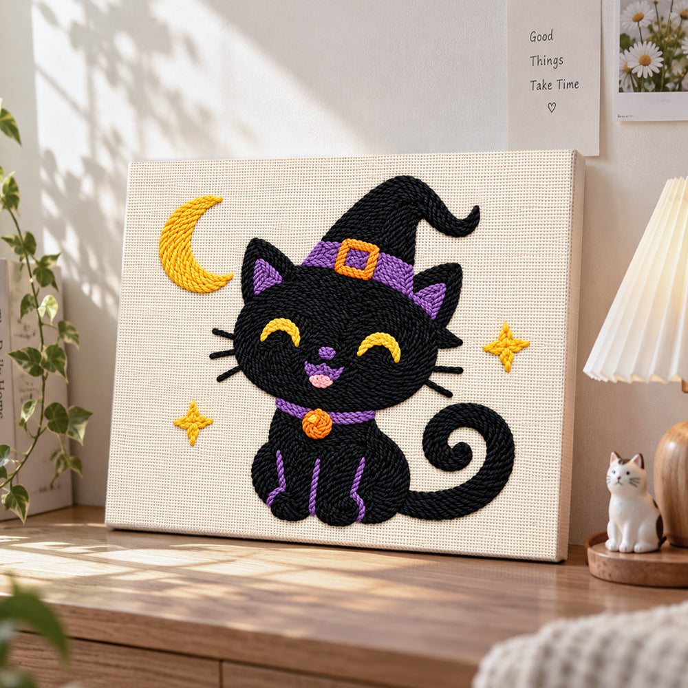 Black witch cat with crescent moon punch needle artwork displayed on a table