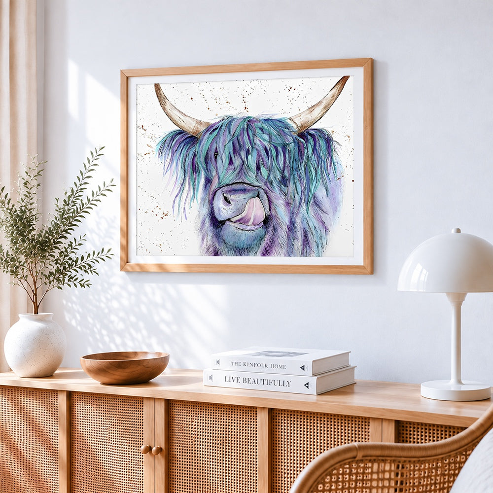 Blue and purple watercolour highland cow cross stitch artwork displayed on wall as home decor