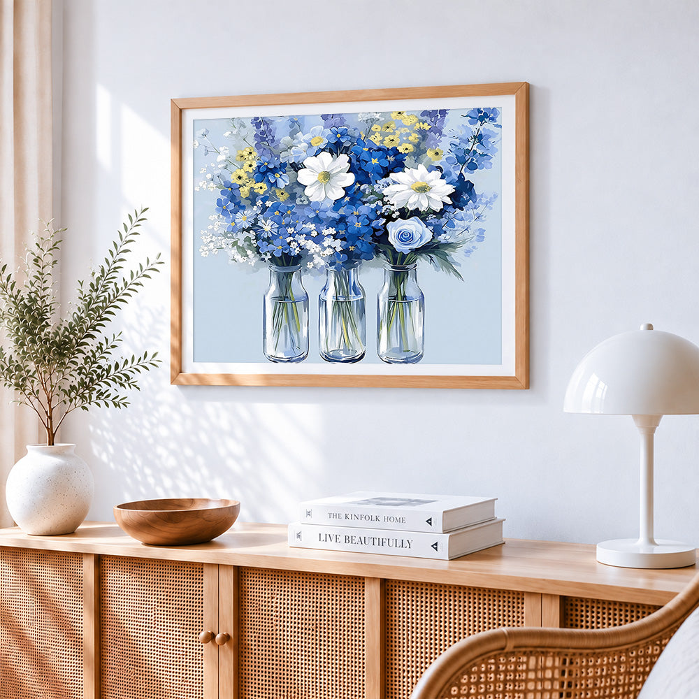 Blue and white wildflowers in glass bottles cross stitch artwork displayed on wall as home decor