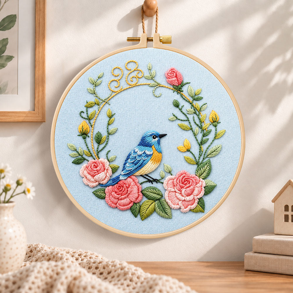 Blue bird inside pink rose wreath embroidery hoop wall art displayed as warm and cosy handmade home decor