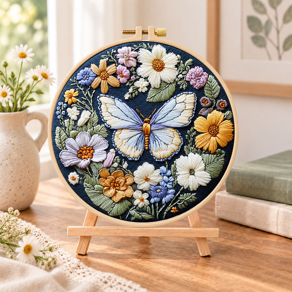 Blue butterfly in wildflower garden embroidery kit finished hoop displayed on a wooden stand as cozy tabletop decor