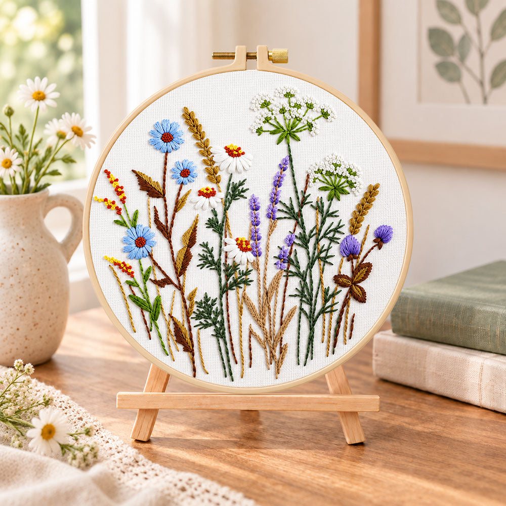 Blue cornflower meadow embroidery kit finished hoop displayed on a wooden stand as cosy tabletop decor