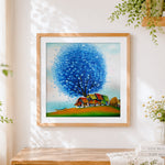 Finished blue tree and colourful village cross stitch artwork displayed