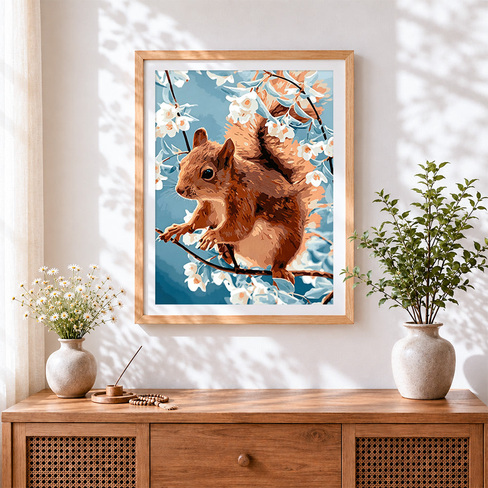 Finished brown squirrel and white blossom cross stitch artwork displayed