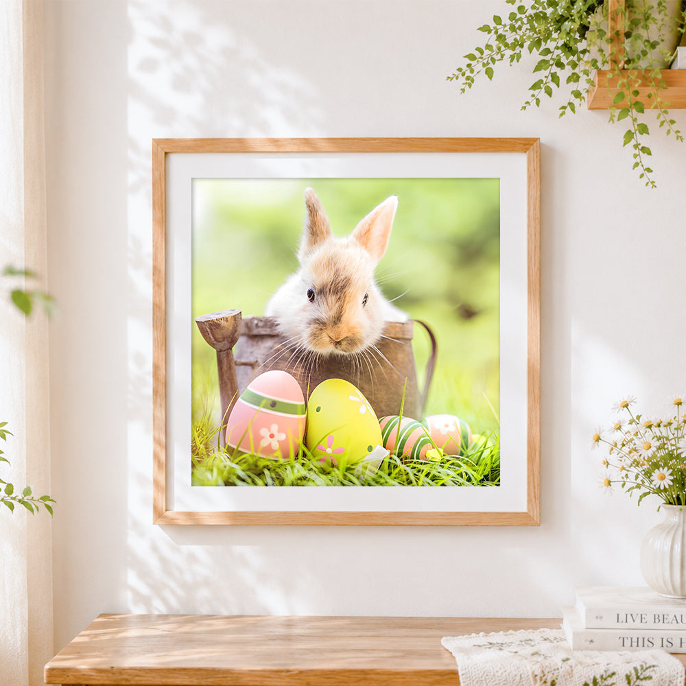 Finished bunny in a watering can with easter eggs cross stitch artwork displayed