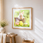 Bunny in a watering can with easter eggs cross stitch artwork displayed on wall as home decor