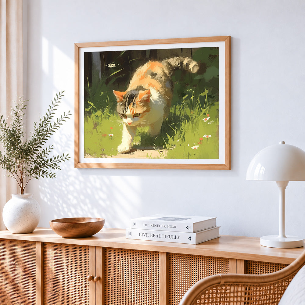 Calico cat stalking in the grass cross stitch artwork displayed on wall as home decor