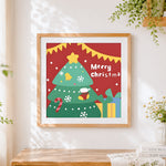 Finished cartoon christmas tree and "merry christmas" cross stitch artwork displayed