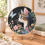 Cat and blue butterfly embroidery kit finished hoop displayed on a wooden stand as cosy tabletop decor