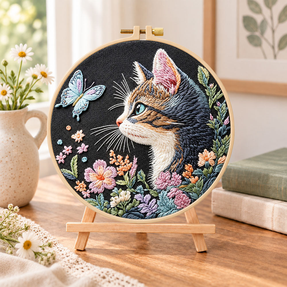 Cat and blue butterfly embroidery kit finished hoop displayed on a wooden stand as cosy tabletop decor