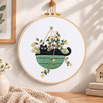Cat in green hanging pot embroidery hoop wall art displayed as warm and cosy handmade home decor