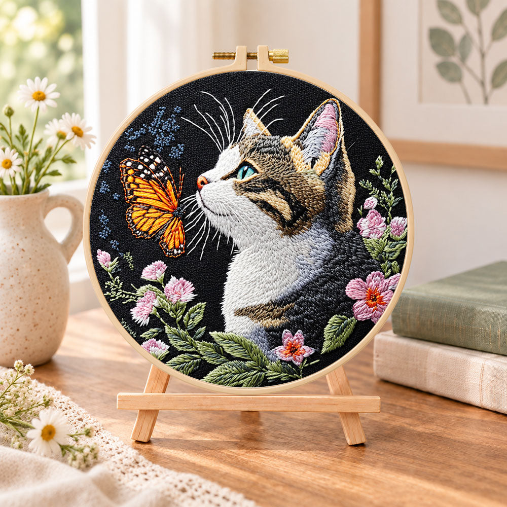 Cat meets monarch butterfly embroidery kit finished hoop displayed on a wooden stand as cosy tabletop decor