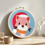 Cat wearing a santa hat punch needle artwork displayed on a table