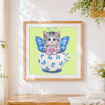 Finished cat with butterfly wings in teacup cross stitch artwork displayed