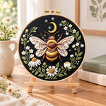 Celestial bee with daisies embroidery kit finished hoop displayed on a wooden stand as cosy tabletop decor