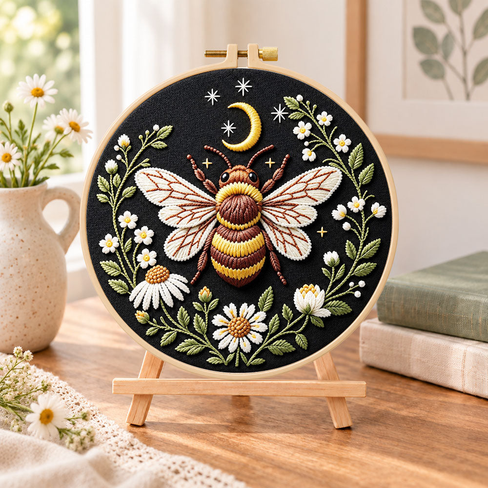 Celestial bee with daisies embroidery kit finished hoop displayed on a wooden stand as cosy tabletop decor