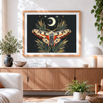 Finished celestial moth and crescent moon cross stitch artwork displayed