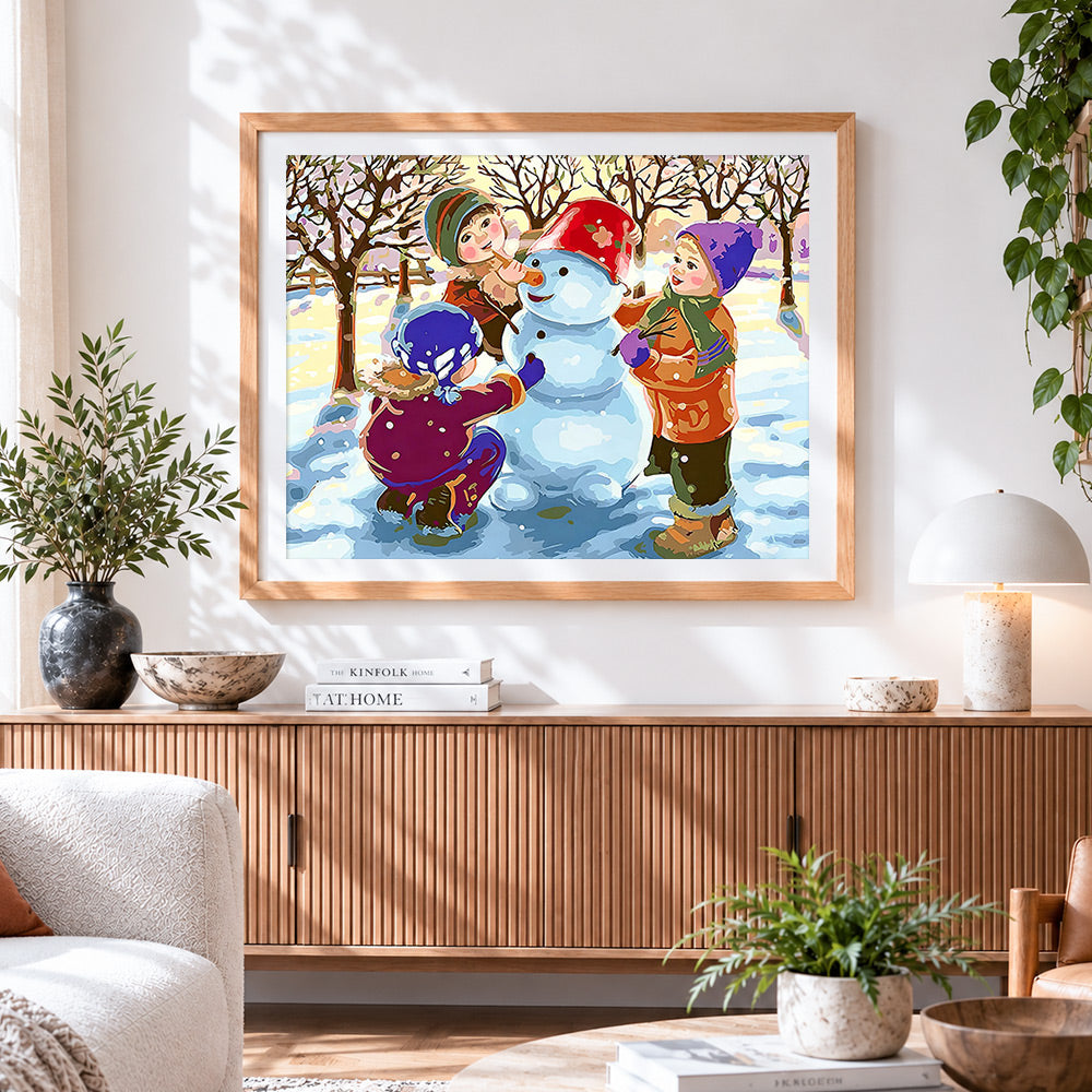 Finished children building a snowman in winter cross stitch artwork displayed