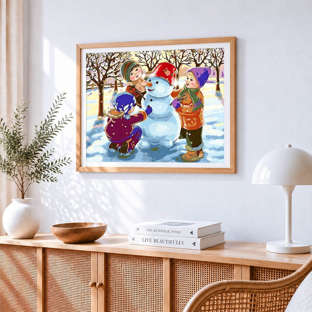 Children building a snowman in winter cross stitch artwork displayed on wall as home decor