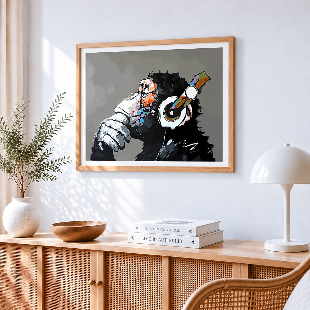 Chimpanzee with headphones cross stitch artwork displayed on wall as home decor