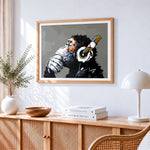 Chimpanzee with headphones cross stitch artwork displayed on wall as home decor