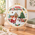 Christmas cabin and tree embroidery kit finished hoop displayed on a wooden stand as cosy tabletop decor