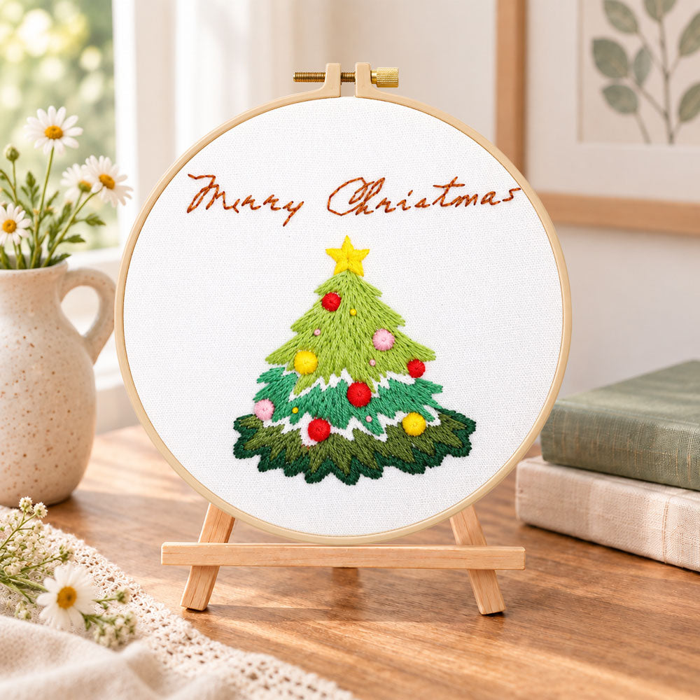 Christmas tree greeting embroidery kit finished hoop displayed on a wooden stand as cosy tabletop decor