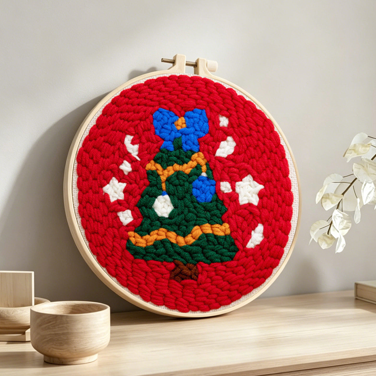 Christmas tree with snowflakes punch needle artwork displayed on a table