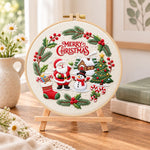 Christmas wreath scene embroidery kit finished hoop displayed on a wooden stand as cosy tabletop decor