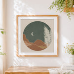 Finished circular minimalist landscape and moon cross stitch artwork displayed