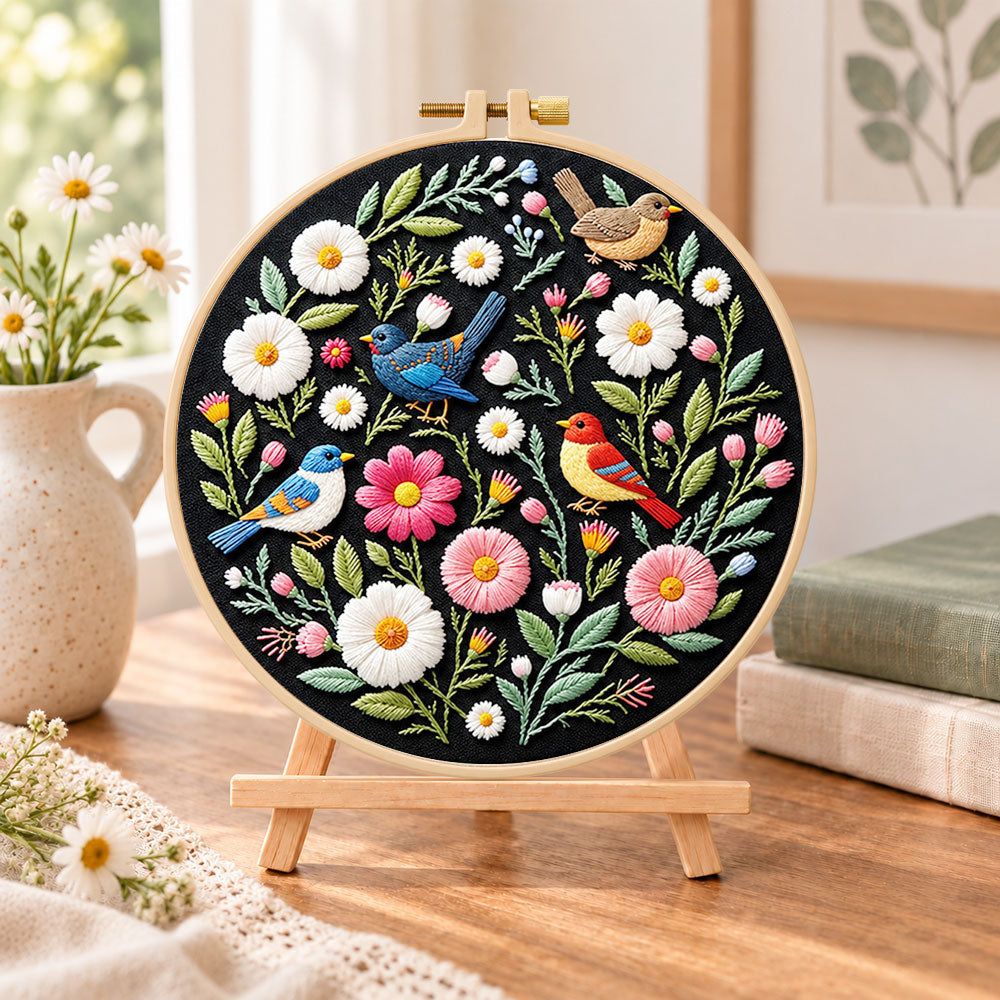 Colourful birds and wildflowers embroidery kit finished hoop displayed on a wooden stand as cosy tabletop decor