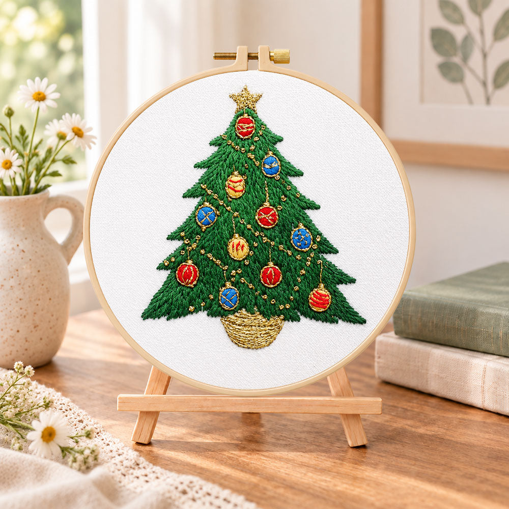 Colourful christmas tree embroidery kit finished hoop displayed on a wooden stand as cozy tabletop decor